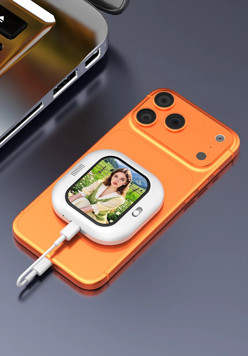 Mini magnetic selfie monitor screen clipped to orange phone, showing live selfie and charging cable