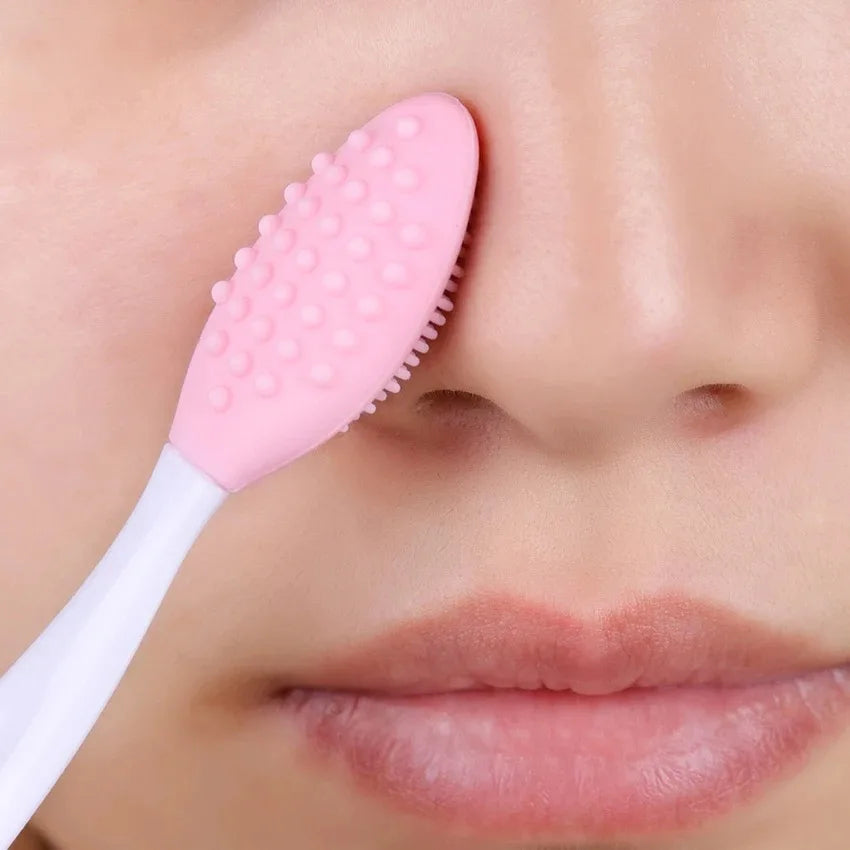 Pink silicone face cleansing brush with soft bristles, near the nose on skin