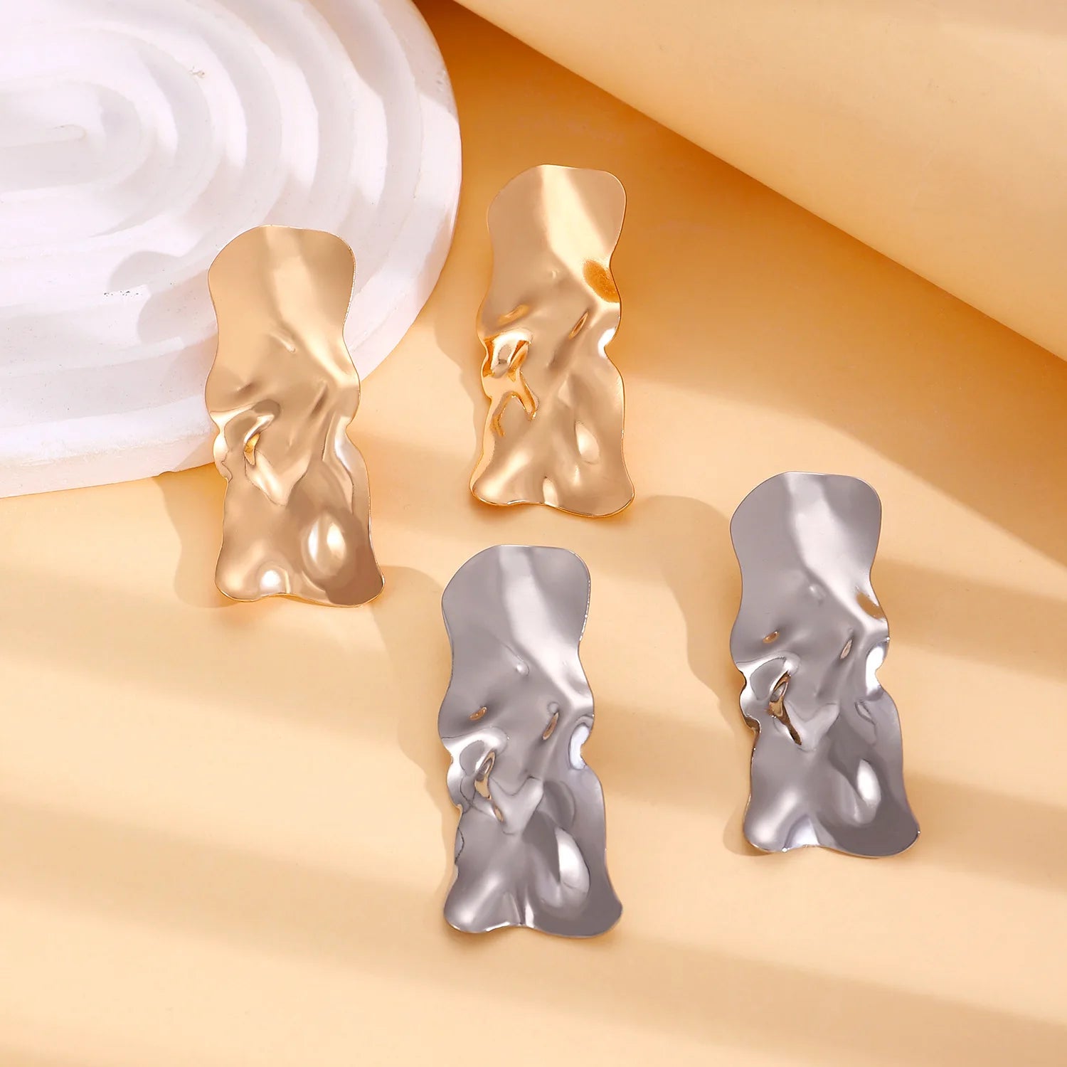 Heart-shaped drop earrings in gold and silver with raised textured surfaces
