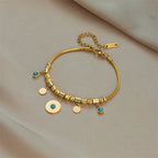 Gold-tone charm bracelet with green stone charms and small coin discs, clasp visible