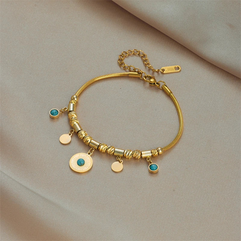 Gold-tone charm bracelet with green stone charms and small coin discs, clasp visible