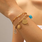 Gold-tone double-layer bracelet with sun, heart, coin charms and turquoise bead
