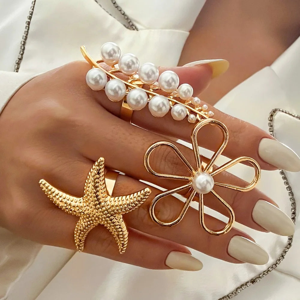 Gold-tone starfish ring with white pearl center, swirl band accents