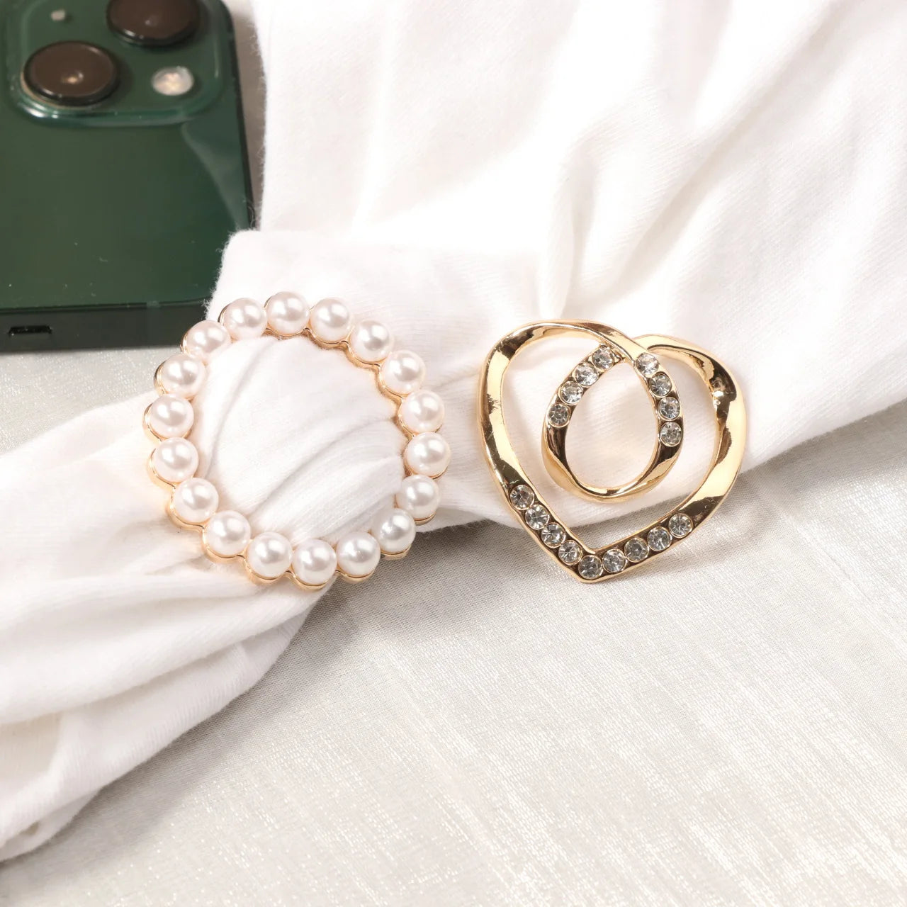 Pearl circle scarf brooch clip and heart-shaped rhinestone brooch clip on white fabric