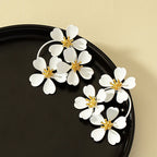 White camellia-style flower dangle earrings with gold-tone star centers and looping hoops