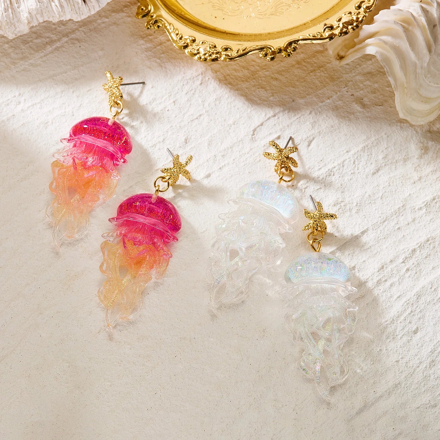 Gold starfish stud earrings with pink and white jellyfish dangling charms.