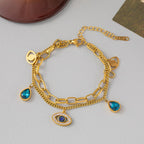 Gold-tone link bangle bracelet with blue teardrop and eye charms