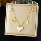 Gold-tone heart pendant necklace with pearl accents, butterfly charm, and flower pendants