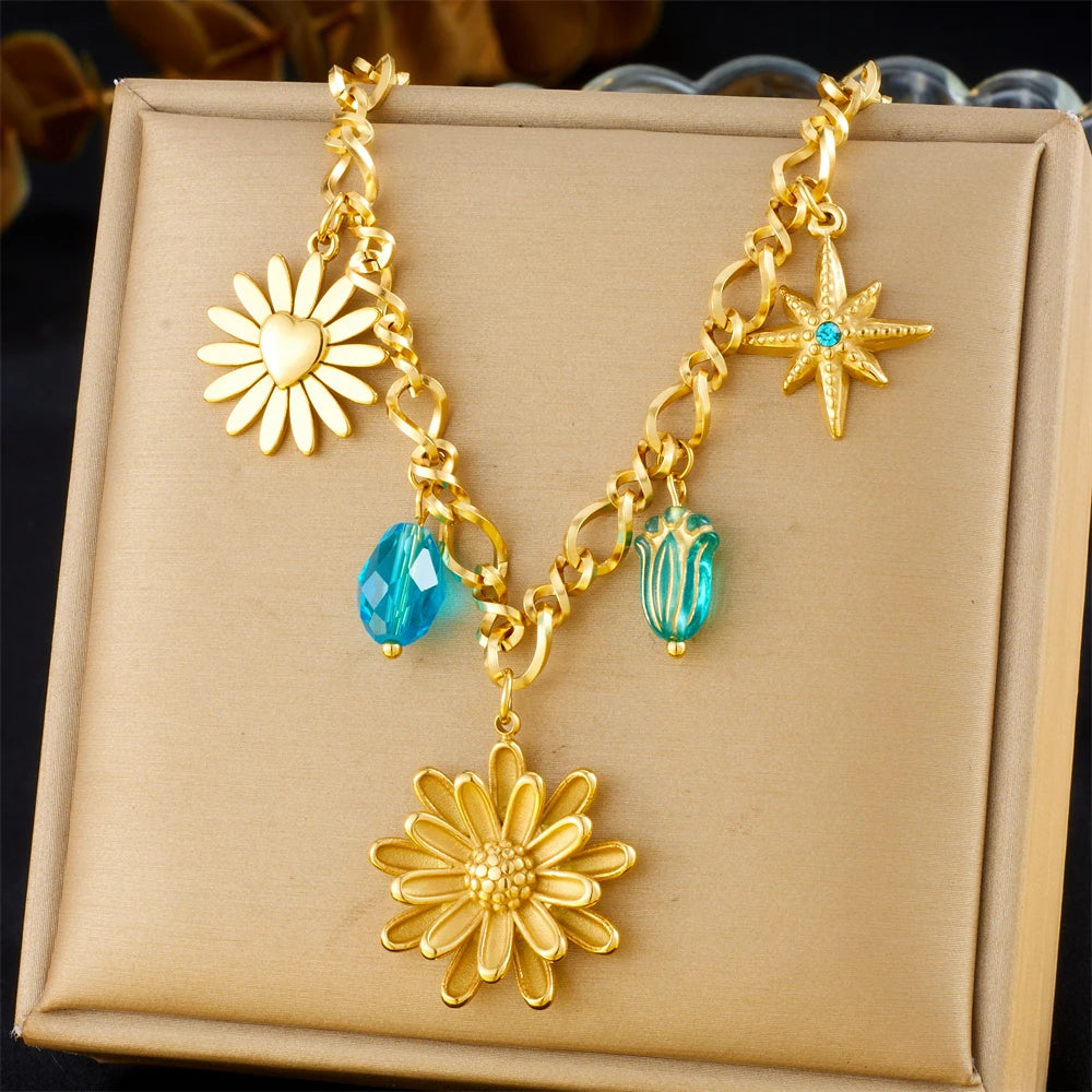 Gold-tone multi-pendant necklace with star, daisy flower, and blue crystal drops
