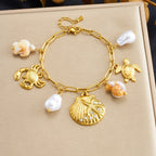 Gold-tone ocean charm necklace with pearl drops and crab/turtle charms with scallop pendant