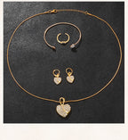 Gold heart pendant necklace with rhinestone details; matching hoop earrings and bangle ring