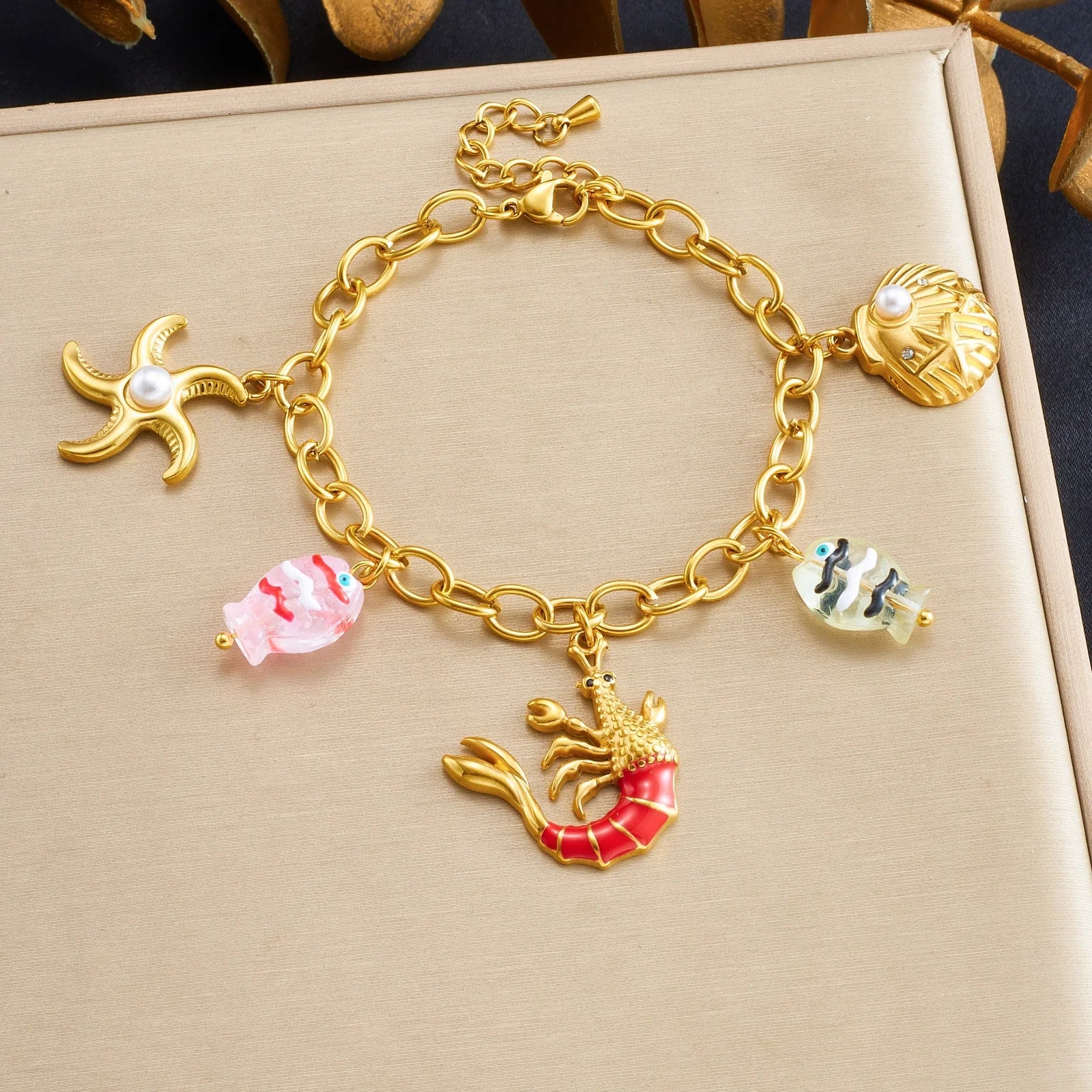 Gold-tone conch shell charm bracelet with colorful fish and starfish charms