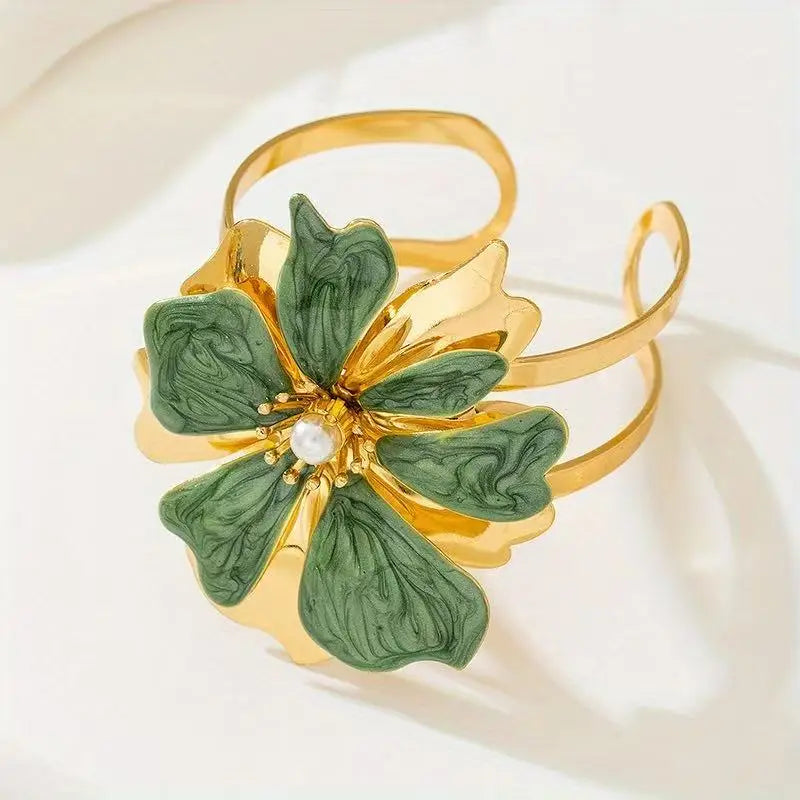 Flower cuff bangle bracelet with gold-tone band and green enamel flower with pearl center.