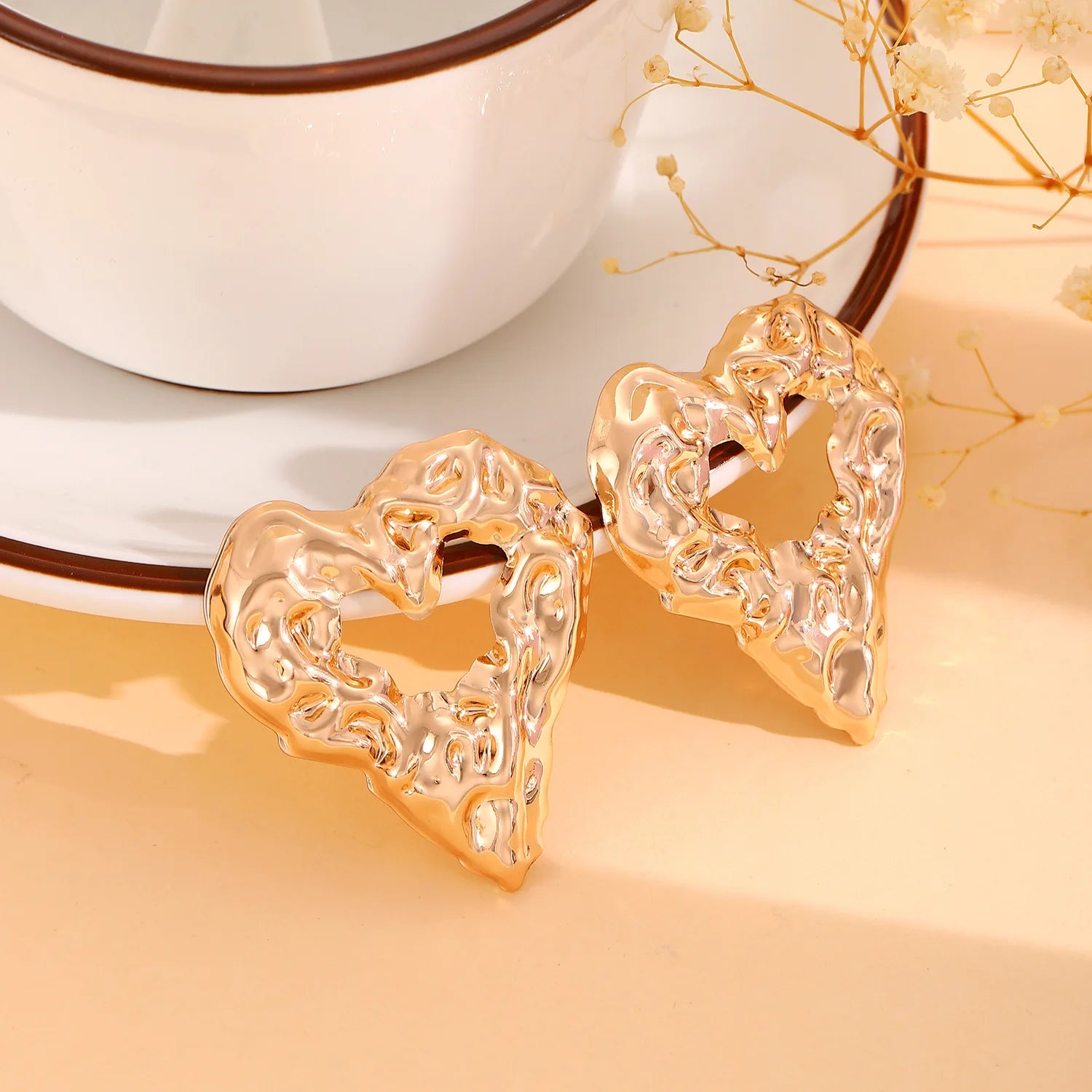 Gold heart-shaped drop earrings with ornate raised texture, pair