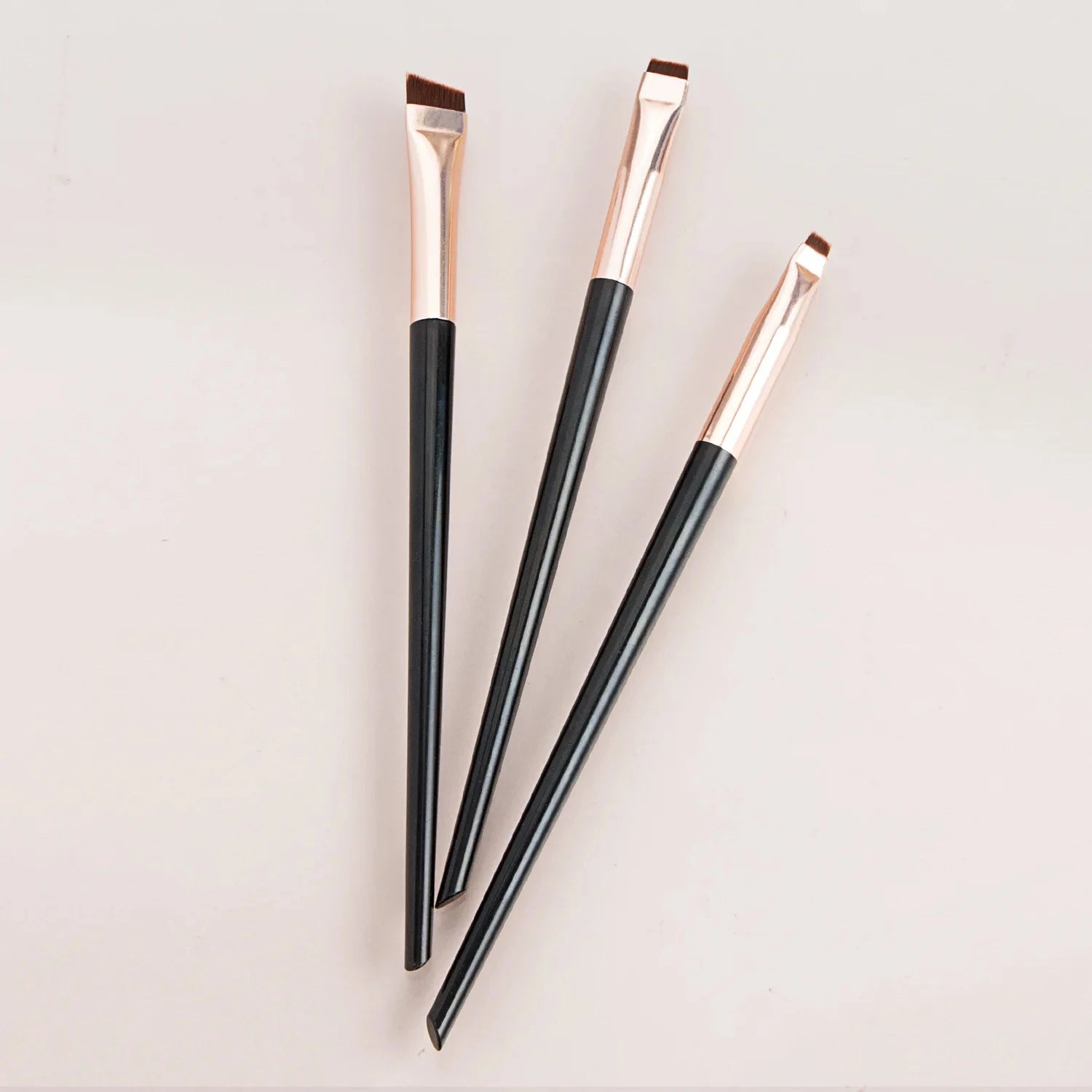 Eyeliner and eyebrow makeup brushes, three slim handles with angled copper bristles
