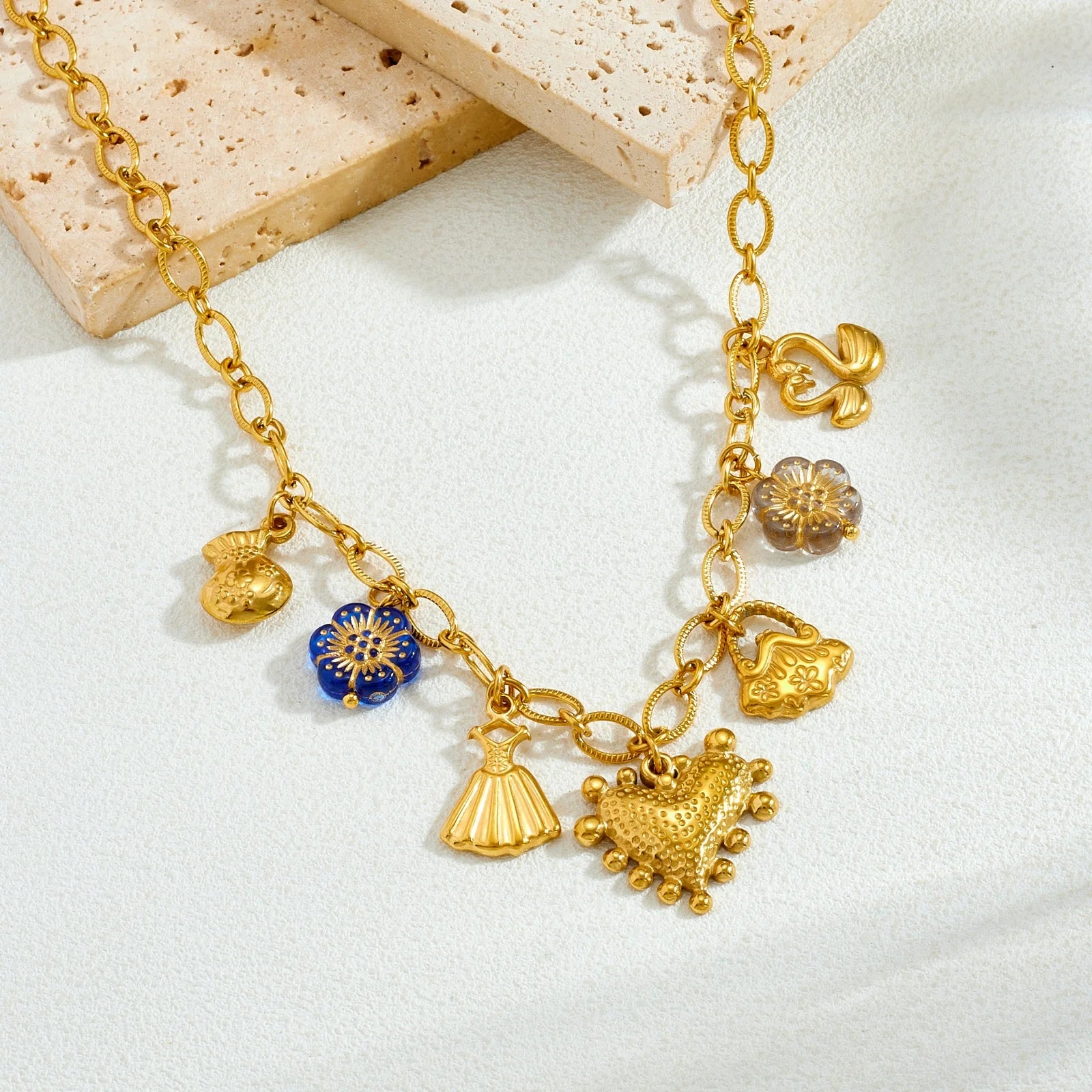 Gold-tone multi-pendant necklace with small tassel and heart charms, some with blue enamel