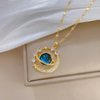 Gold-tone planet pendant necklace with blue gemstone and star-and-moon halo setting