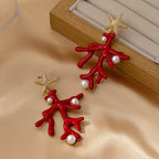Red coral starfish earrings with gold-tone starfish and pearl-like beads beside a box