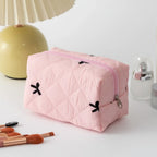 Light pink quilted cosmetic bag with black bow embroidery and zip closure