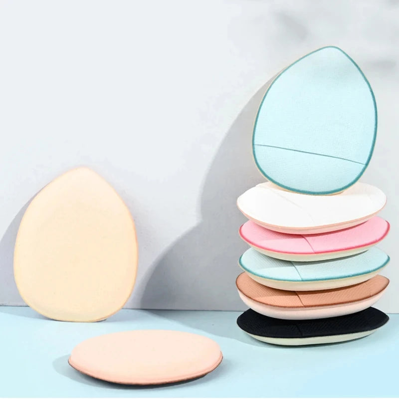 Stack of teardrop finger puff sponges in light blue, white, pink, tan, and black.