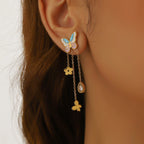 Butterfly stud earrings with blue enamel wings and dangling gold chains with flower charms