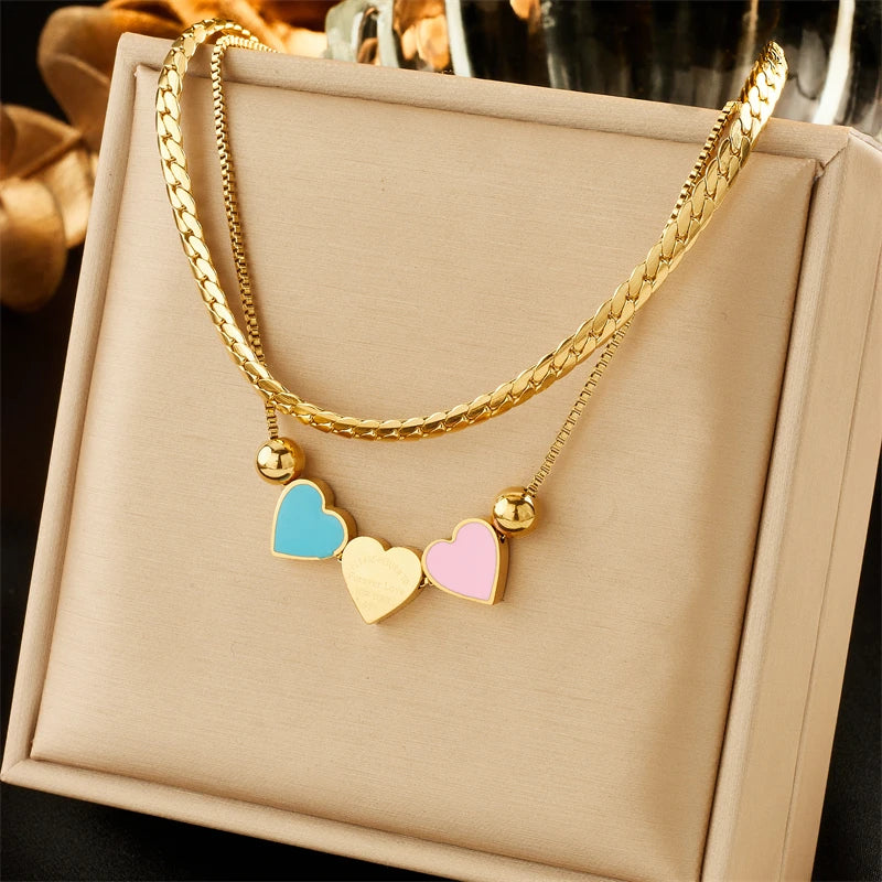 Gold heart charm double-chain necklace with blue, pink, and cream enamel heart charms