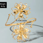 Gold flower upper arm bracelet with coiled petal design and chain cuffs