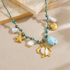 Sea turtle, starfish, and shell pendants on turquoise beaded necklace with white accents