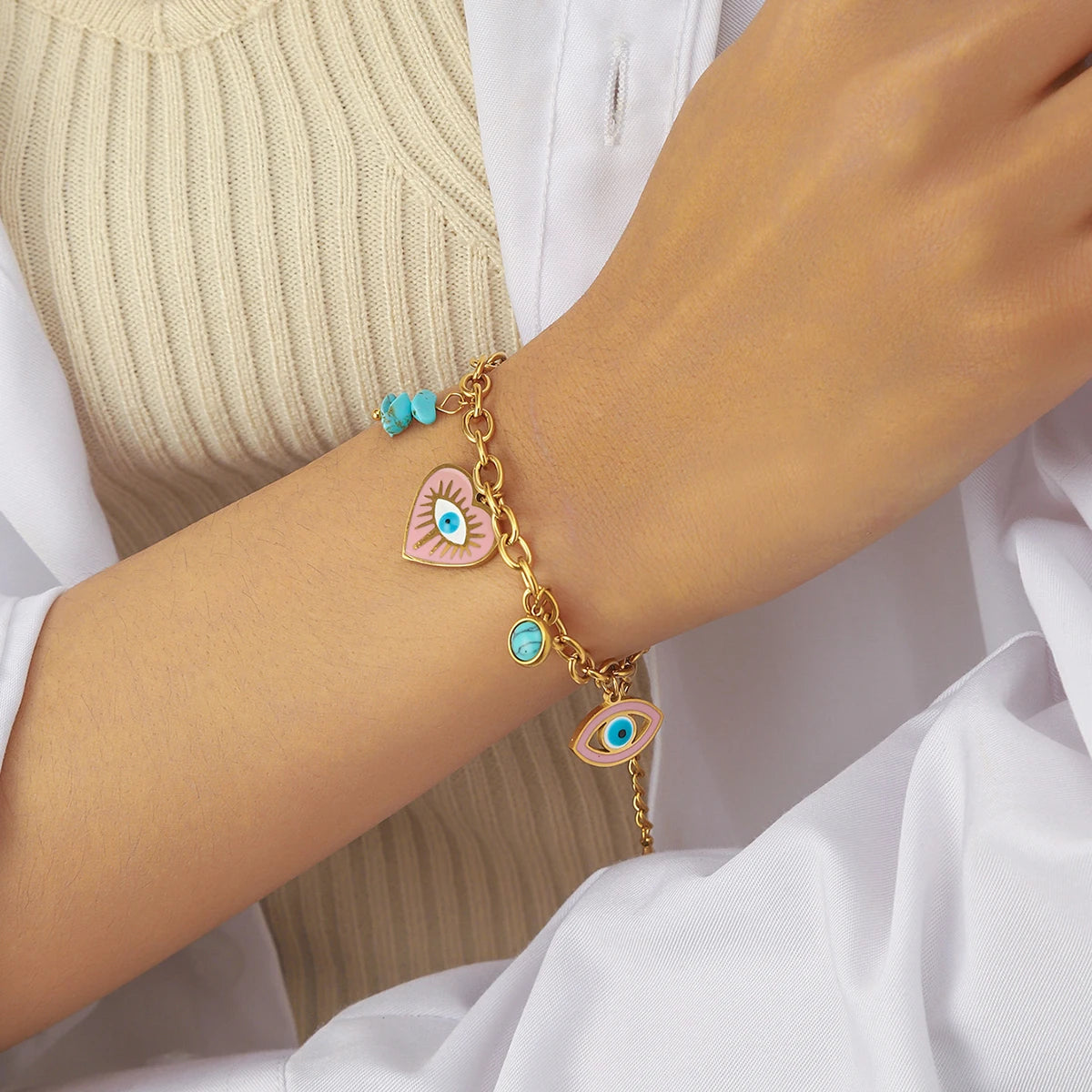 Gold-tone evil-eye heart bracelet with turquoise bead charm, worn on wrist