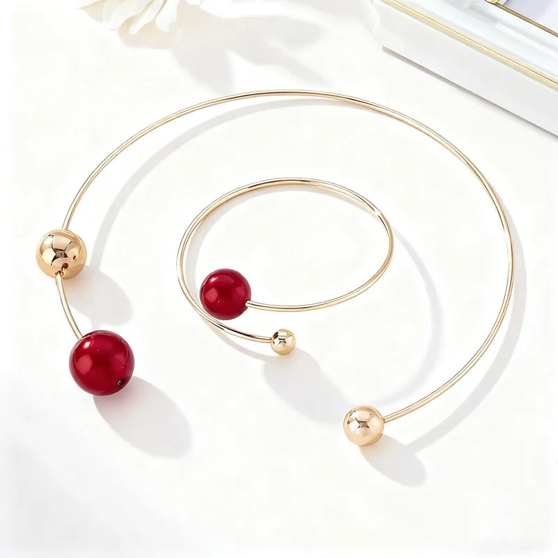 Gold-tone collar and bracelet set with red pearl beads and small round gold accents