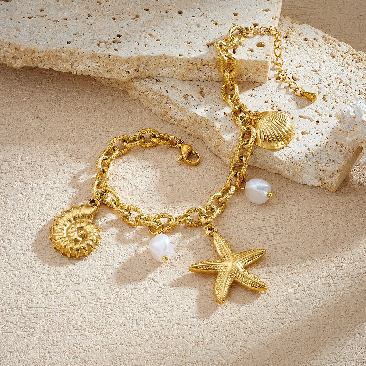 Gold-tone charm necklace with seashell, disc, starfish, and white pearl drop charms