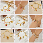 Gold-tone enamel ocean charm bracelet with seashells and multicolor fish charm dangles