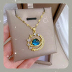 Gold-tone planet pendant necklace with blue gemstone, star accents, and zircon details
