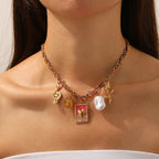 Gold-tone necklace with rainbow chain, pink heart charm, white pearl, and amber drops