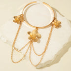 Gold flower upper arm bracelet with three dangling chain strands and flower charms