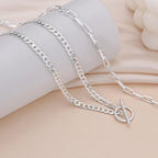 Silver layered chain necklace with oval connector; Cuban link and paperclip styles