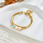 Gold heart charm bracelet with blue, pink, and cream enamel heart dangles