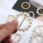 Round pearl scarf brooch clip with a gold-tone pin closure, hand held