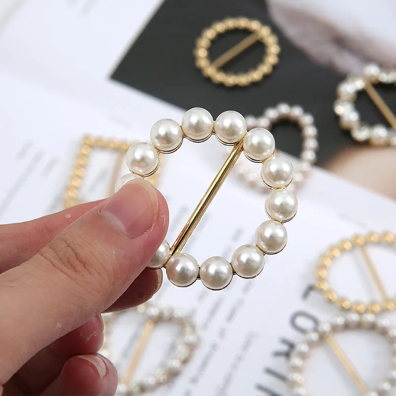 Round pearl scarf brooch clip with a gold-tone pin closure, hand held