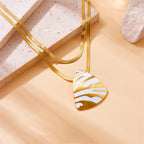 Gold-tone chain necklace with white tiger stripe teardrop pendant, close-up
