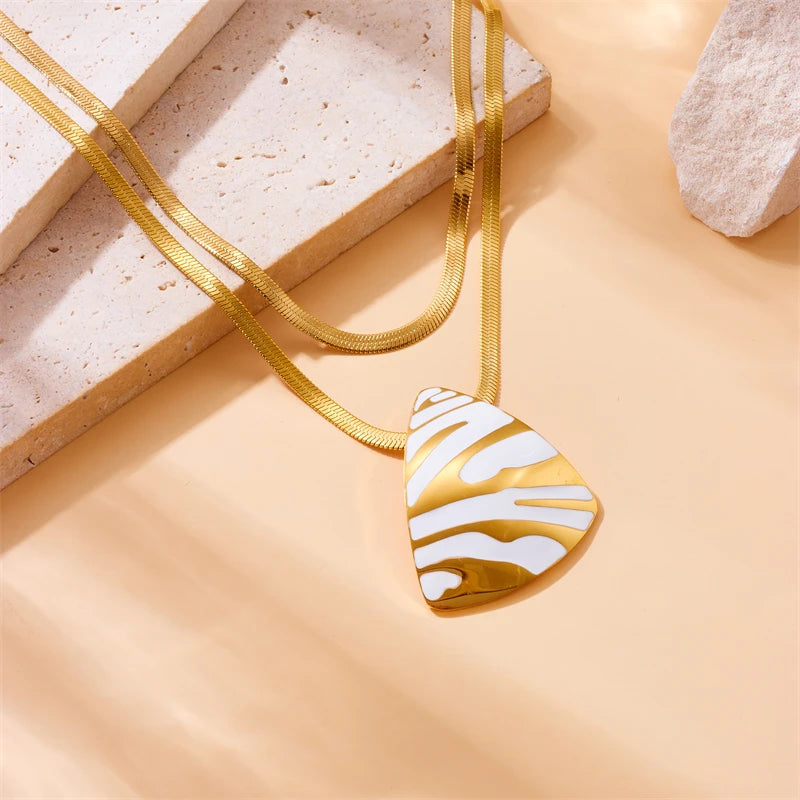 Gold-tone chain necklace with white tiger stripe teardrop pendant, close-up