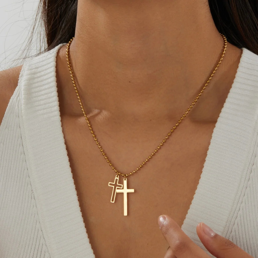 Gold cross pendant necklace with two small cross charms on a fine chain