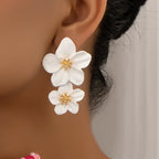 White double-layer flower dangle earrings with gold-tone centers, two stacked petals