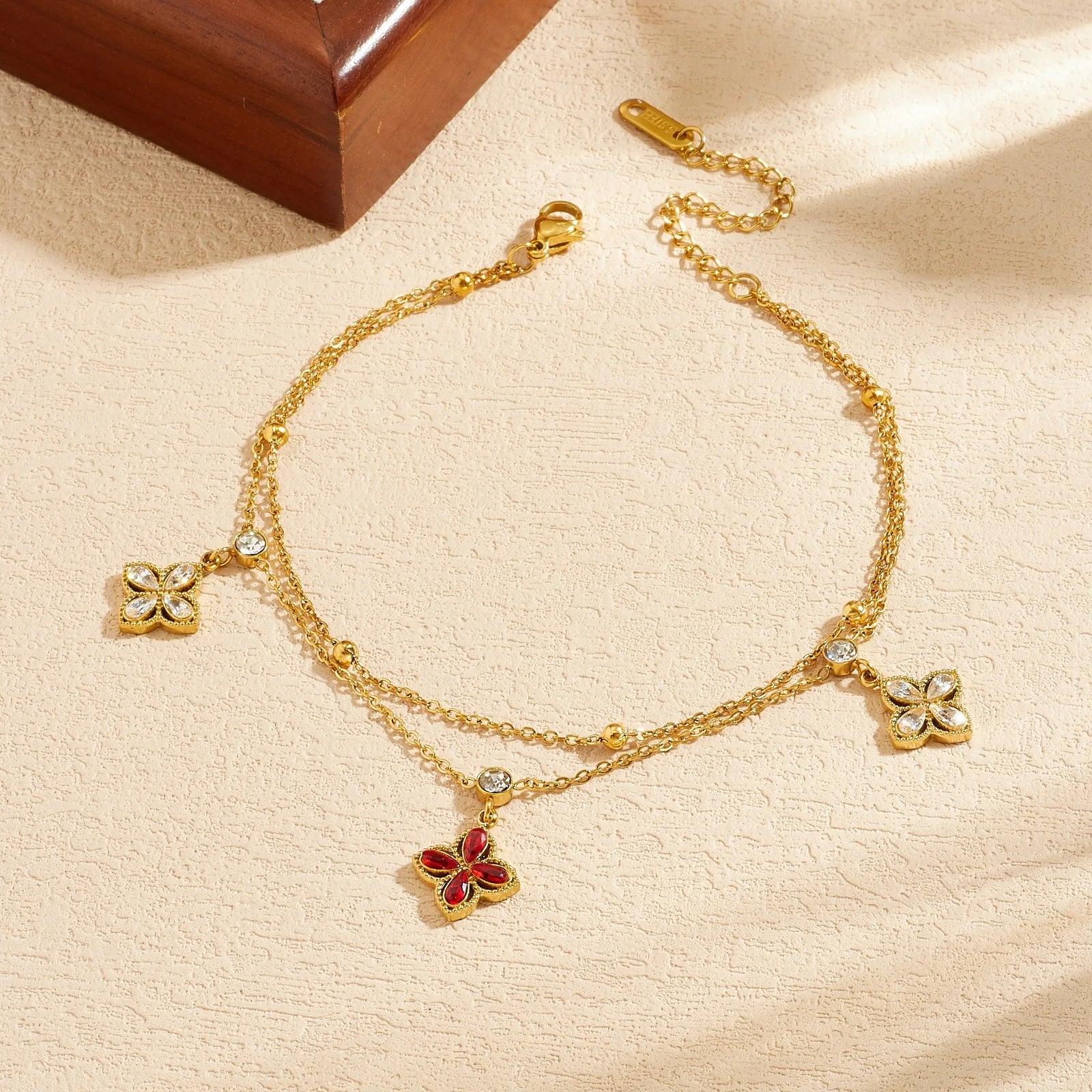 Gold-tone flower charm bracelet with red pendant and multiple white crystal flower accents