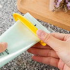 Yellow toothpaste tube squeezer dispenser with metal channel, gripping a tube in hand