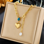 Gold lariat necklace with blue teardrop stone, heart charm, and pearl drop