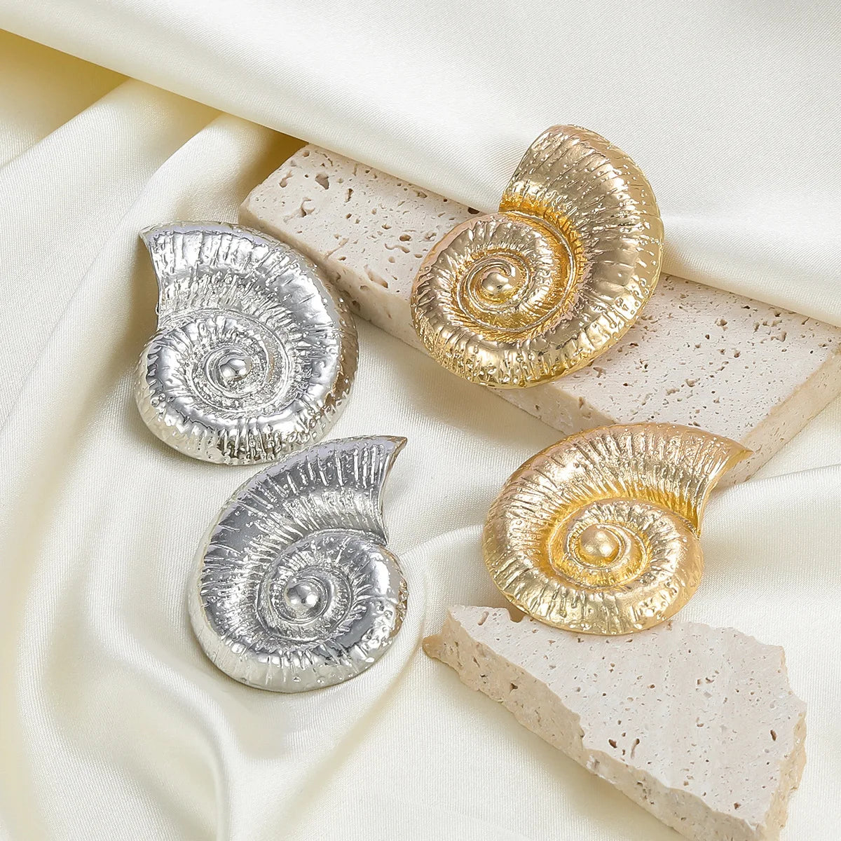 Conch shell stud earrings set in silver and gold tones with round spiral details