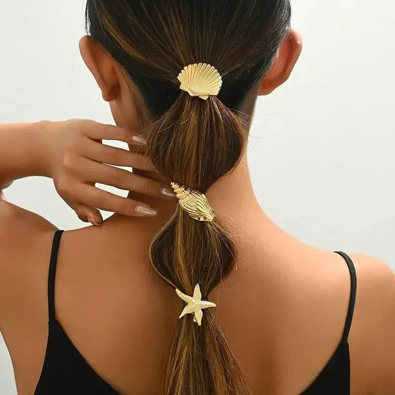 Gold starfish and shell hair clips on a ponytail, with two shell pieces visible