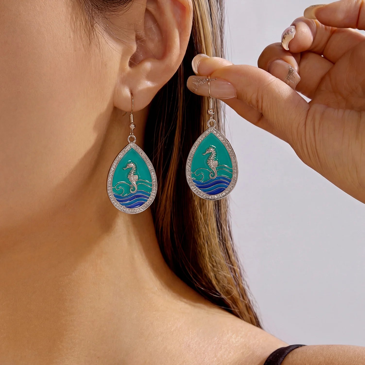 Teardrop seahorse drop earrings with teal enamel and crystal border