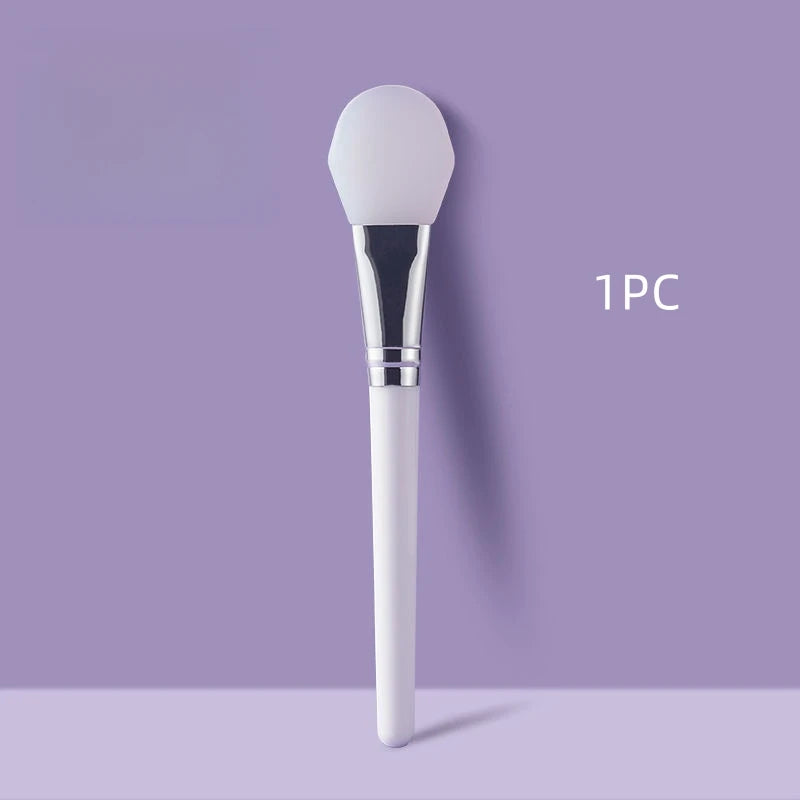 Face mask brush with rounded white silicone head and chrome collar, white handle